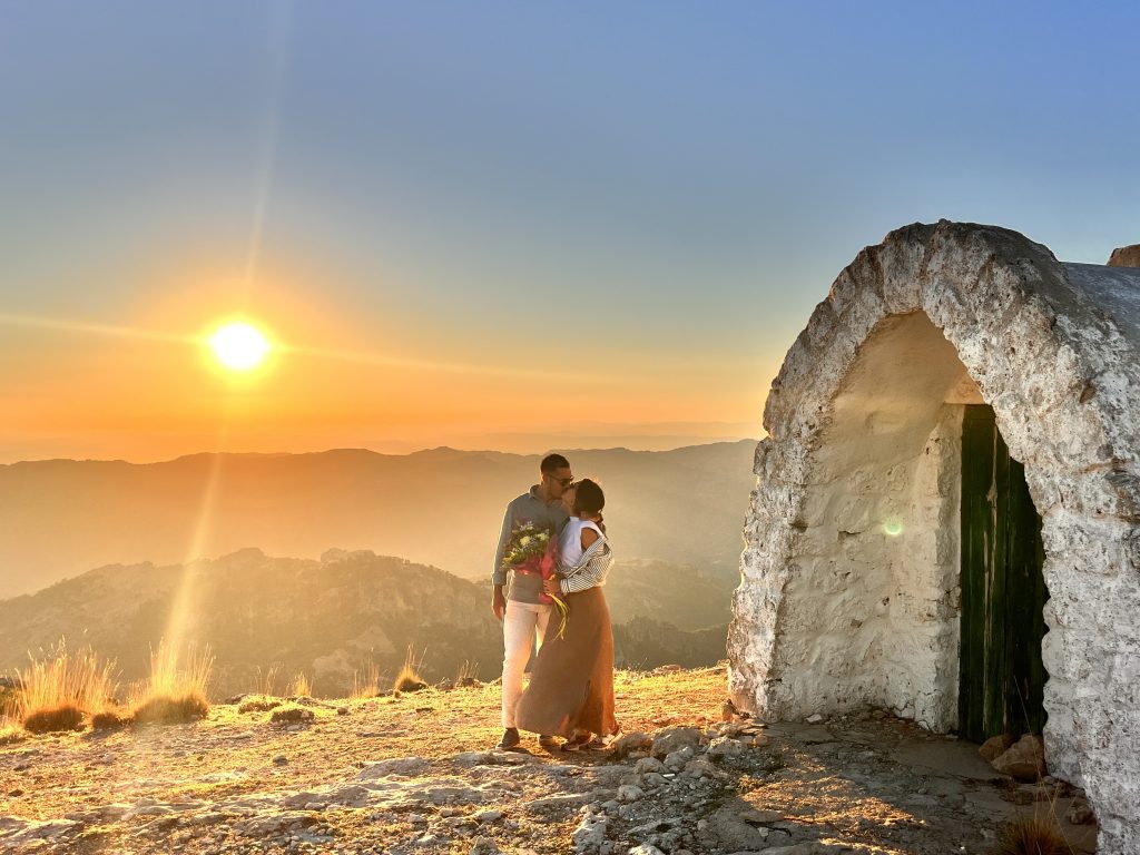Novios besándose en una pedida de mano en el puntal de los canteros al atardecer